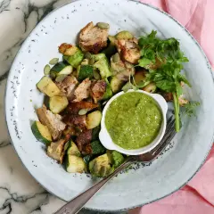 En tallrik med kyckling, zucchini och pumpafrön, serverad med en grön sås. En perfekt snabb nyttig lunch för en solig dag.