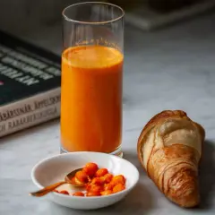 Frukost med en croissant, ett glas apelsinjuice och en skål havtorn. Kanske ett havtorn recept?