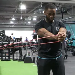 Man utför pallof press med gummiband i ett gym.