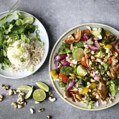 En tallrik med ris, koriander och lime, bredvid en annan med kyckling, broccoli, paprika, cashewnötter och lök. Ett perfekt recept nyttig mat!