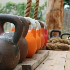 En rad kettlebells i olika färger och vikter, redo för nya reps och set. Ett rep ligger bredvid, redo för träning.