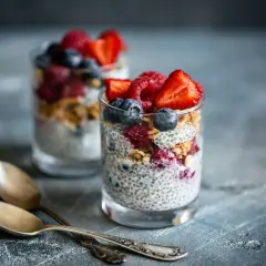 Två glas med chiapudding, toppad med bär och granola. Perfekt för en hälsosam frukost med koll på chiapudding kalorier.