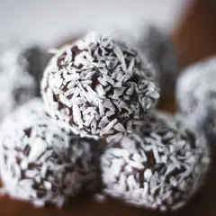 Nära bild på protein chokladbollar täckta med kokosflingor. Perfekt för ett snabbt mellanmål.