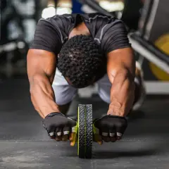 Man gör en ab wheel rollout i gymmet, med fokus på magmusklerna.