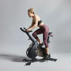 Kvinna tränar intensivt på motionscykel, redo för tuffa tabata intervaller.