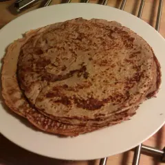 En hög med tunna pannkakor på en vit tallrik. Perfekt protein frukost för att gå ner i vikt.