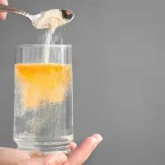 Pulver hälls från en sked ner i ett glas vatten, kanske för att motverka elektrolyter brist.