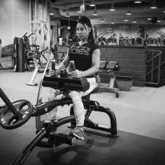 Kvinna tränar vaderna på en sittande vadpress-maskin i ett modernt gym.