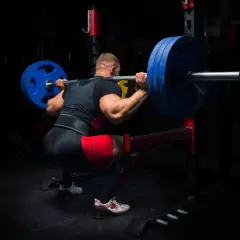 Stark man gör en tung knäböj med skivstång, redo för sitt madcow 5x5 pass.
