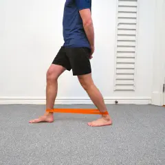 Man med orange band runt anklarna för att träna bort stela fotleder.