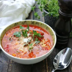 En mustig tomatsoppa med ris och örter, en perfekt källa till vegetariskt protein. Serveras med en sked och pepparkvarn.
