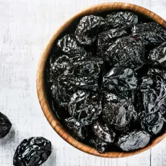 En skål med mörka, skrynkliga katrinplommon. Perfekt för en mage som behöver lite hjälp.