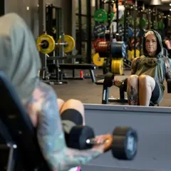En kvinna med tatuerad crossfit kropp lyfter vikter på gymmet.