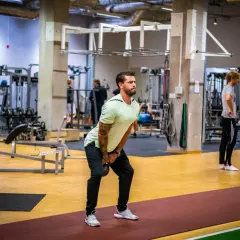 Man utför ett helkroppspass på gym med kettlebell.