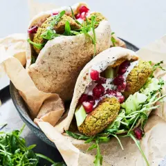 Två läckra pitabröd fyllda med ugnsbakad falafel, färska grönsaker, krämig sås och granatäppelkärnor.