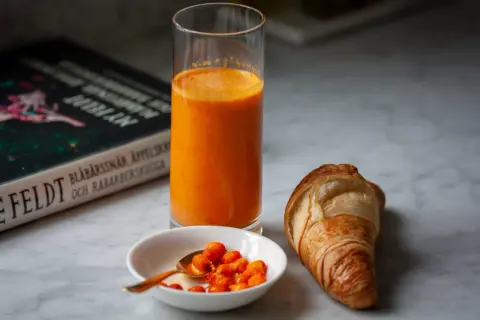 Frukost med en croissant, ett glas apelsinjuice och en skål havtorn. Kanske ett havtorn recept?