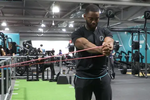 Man utför pallof press med gummiband i ett gym.