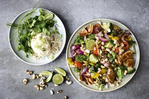 En tallrik med ris, koriander och lime, bredvid en annan med kyckling, broccoli, paprika, cashewnötter och lök. Ett perfekt recept nyttig mat!