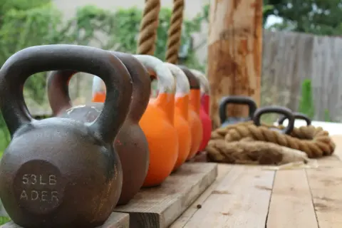 En rad kettlebells i olika färger och vikter, redo för nya reps och set. Ett rep ligger bredvid, redo för träning.