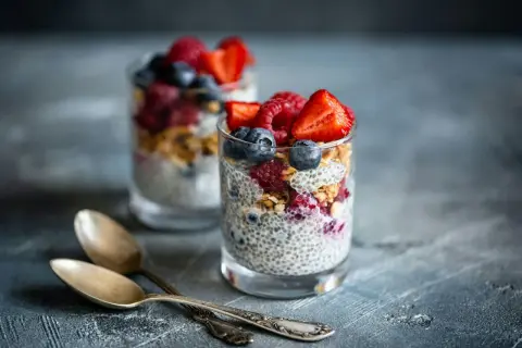 Två glas med chiapudding, toppad med bär och granola. Perfekt för en hälsosam frukost med koll på chiapudding kalorier.