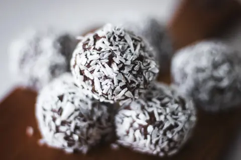Nära bild på protein chokladbollar täckta med kokosflingor. Perfekt för ett snabbt mellanmål.
