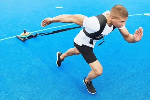 Man drar en släde på blått underlag, en övning som visar hur man hittar motivation genom fysisk ansträngning.