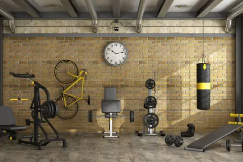 Ett komplett hemmagym med vikter, boxningssäck, cykel och träningsbänk. Perfekt för att bygga hemmagym i industriell stil.