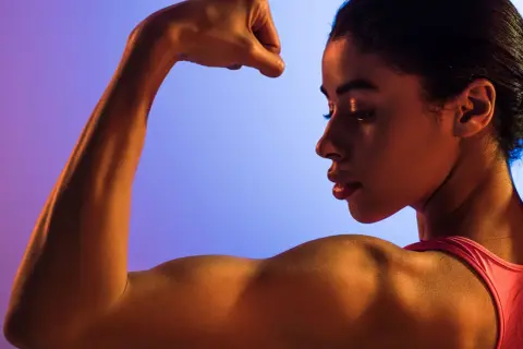 En kvinna visar upp sin muskulösa arm, en symbol för styrka. Även med mindre styrka kan man uppnå fantastiska resultat.