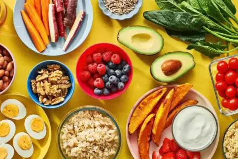 En färgsprakande dukning med proteinrik vegetarisk mat: bönor, ägg, nötter, bär, grönsaker och quinoa.