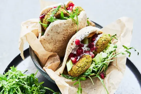 Två läckra pitabröd fyllda med ugnsbakad falafel, färska grönsaker, krämig sås och granatäppelkärnor.