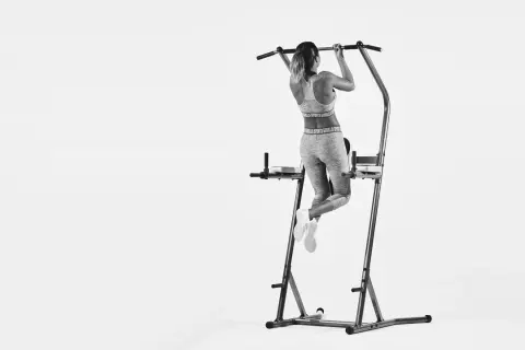 Kvinna tränar pull-ups och bygger starka chins muskler på ett träningsställ.
