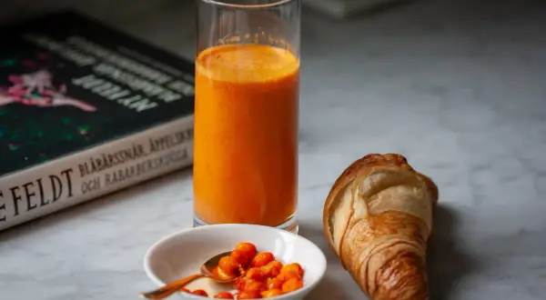 Frukost med en croissant, ett glas apelsinjuice och en skål havtorn. Kanske ett havtorn recept?