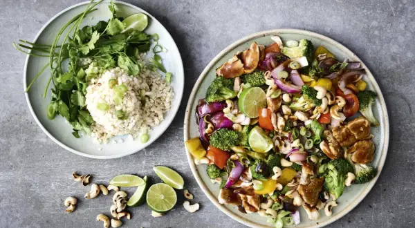 En tallrik med ris, koriander och lime, bredvid en annan med kyckling, broccoli, paprika, cashewnötter och lök. Ett perfekt recept nyttig mat!