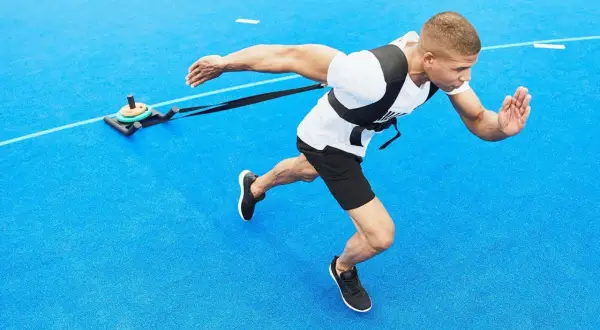 Man drar en släde på blått underlag, en övning som visar hur man hittar motivation genom fysisk ansträngning.