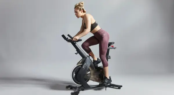 Kvinna tränar intensivt på motionscykel, redo för tuffa tabata intervaller.