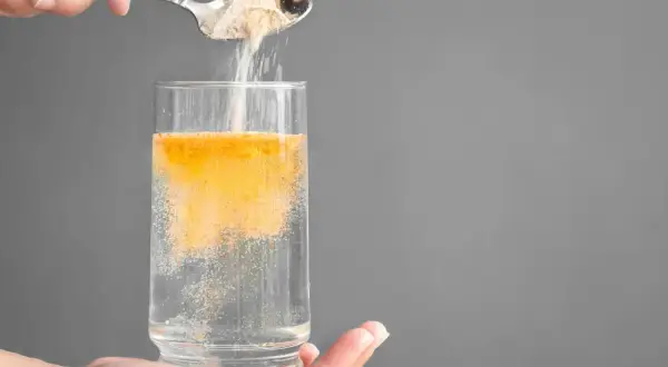 Pulver hälls från en sked ner i ett glas vatten, kanske för att motverka elektrolyter brist.