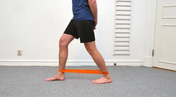 Man med orange band runt anklarna för att träna bort stela fotleder.