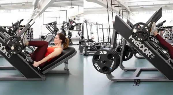 Kvinna tränar benpress i gym. Hon pressar vikter med benen på en Precor-maskin.