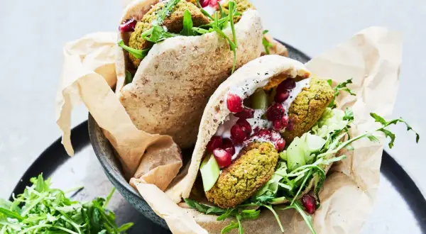 Två läckra pitabröd fyllda med ugnsbakad falafel, färska grönsaker, krämig sås och granatäppelkärnor.