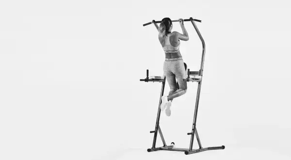 Kvinna tränar pull-ups och bygger starka chins muskler på ett träningsställ.