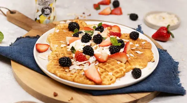 Ljuvliga protein våfflor toppade med färska bär, grädde och kokosflingor. En perfekt start på dagen!