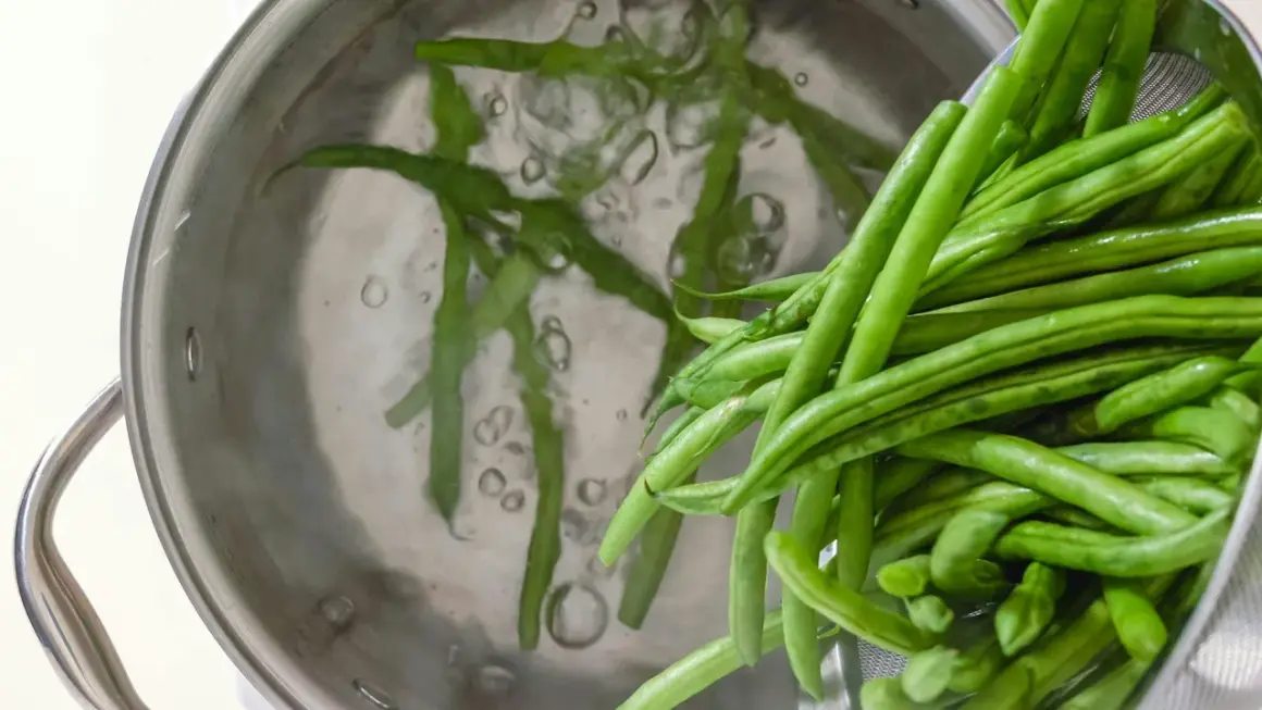 Färska haricots verts kokas i en kastrull. Dessa gröna bönor är nyttiga och en bra källa till vitaminer.