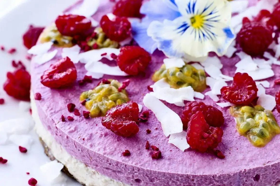 En vacker, lila tårta toppad med hallon, passionsfrukt, kokosflingor och en blå blomma. Perfekt för dig som söker nyttiga kakor.
