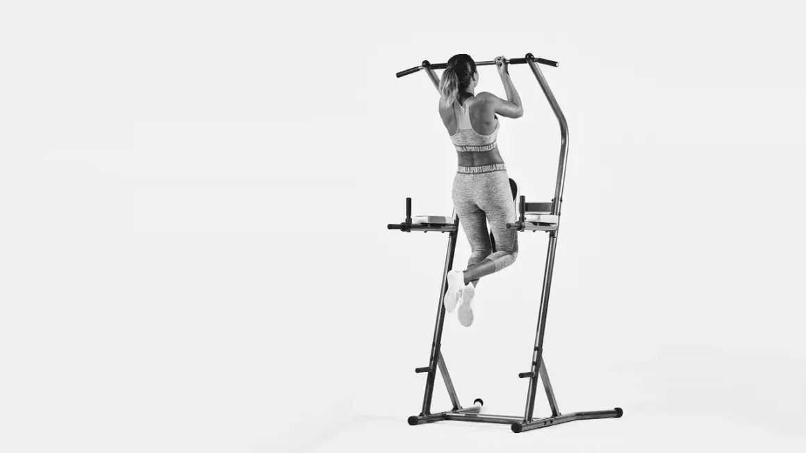 Kvinna tränar pull-ups och bygger starka chins muskler på ett träningsställ.