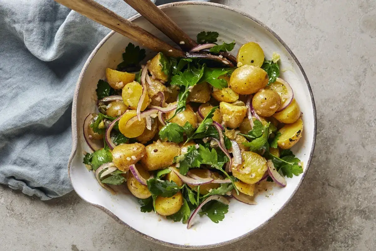 En skål med klassisk svensk potatissallad med färsk persilja och rödlök. Perfekt för att avgöra hur mycket potatissallad per person som behövs till midsommar.