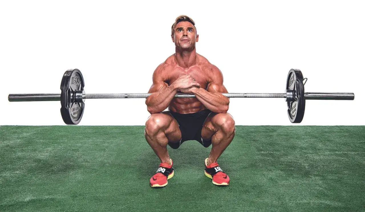 Muskul&ouml;s man utf&ouml;r en zercher squat med skivst&aring;ng i armvecken.