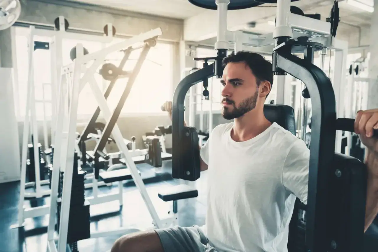 Man tr&auml;nar br&ouml;stmusklerna p&aring; en flyes maskin i ett gym.