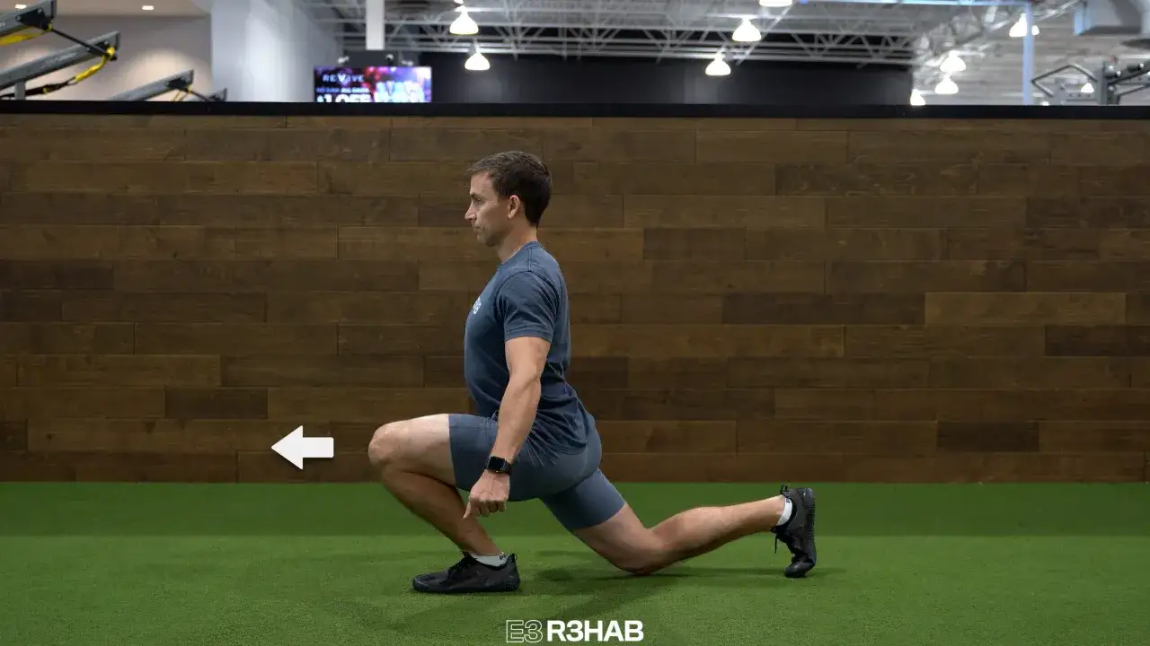 Man utför split squats på ett gym. En vit pil pekar åt vänster.