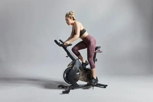 Kvinna tränar intensivt på motionscykel, redo för tuffa tabata intervaller.