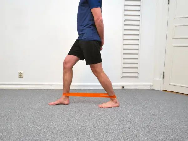 Man med orange band runt anklarna för att träna bort stela fotleder.